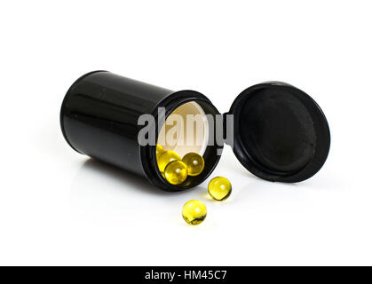 Kleine runde gelbe Gelatinekapseln in schwarzem Glas Stockfoto