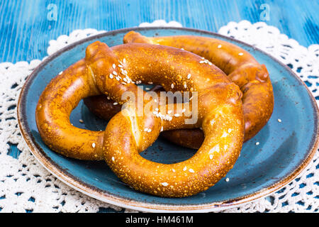 Frisch gebackene Brezeln mit Salz und Käse auf blauem Hintergrund Stockfoto