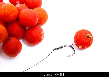 Nahaufnahme der Angeln Köder für Karpfen. Zubehör für Karpfen. Blick auf Angelhaken und mehrere rote Boilies isoliert auf weißem Hintergrund. Stockfoto