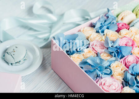 Rosa Feld mit Blumen und Makronen auf eine Untertasse in der Nähe von das blaue Band auf dem Tisch, Ansicht von oben Stockfoto