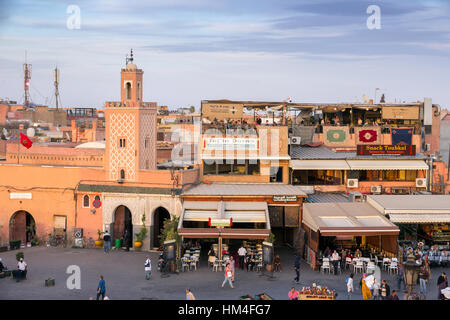Marrakesch, Marokko - 29. April 2016: Moschee und Restaurants mit Touristen auf dem Platz Djemaa el Fna in Marrakesch Stockfoto