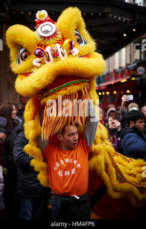 Tänzer mit einem gelben Löwen Kostüm Teilnahme an eine Chinesische Neujahrsparade. Stockfoto