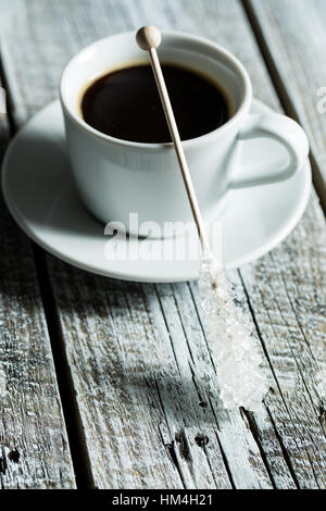 Kristallisierter Zucker auf Holzstab und Kaffeetasse auf alten Holztisch. Stockfoto