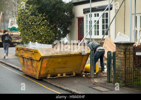 Bauherren Abfall Müll überspringen, auf Bürgersteig & gelb, Line gefüllt / geladenen Generator laden während überspringt, die LKW wartet. UK Stockfoto