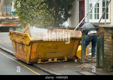 Bauherren Abfall Müll überspringen, auf Bürgersteig & gelb, Line gefüllt / geladenen Generator laden während überspringt, die LKW wartet. UK Stockfoto