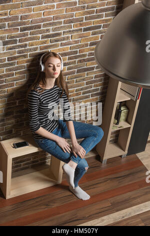 Junge Frau Musik hören mit Kopfhörern zu Hause Stockfoto