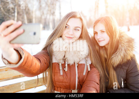 Zwei lächelnde Mädchen machen Selfie in Winter park Stockfoto