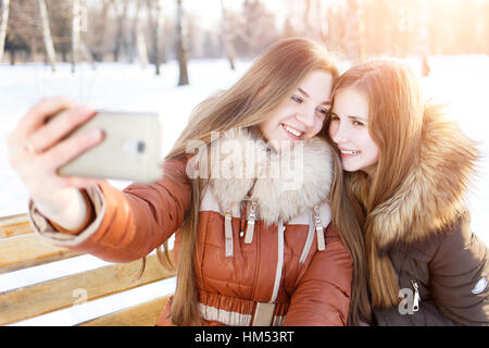 Zwei lächelnde Mädchen machen Selfie in Winter park Stockfoto