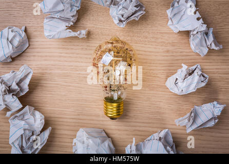 Glühbirne und Zeichnung Graph im Inneren mit zerknüllte Papier auf Holz Hintergrund Stockfoto