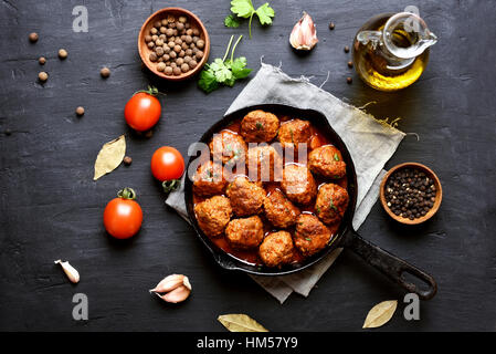 Fleischbällchen in Tomatensauce auf schwarzem Hintergrund, Ansicht von oben Stockfoto