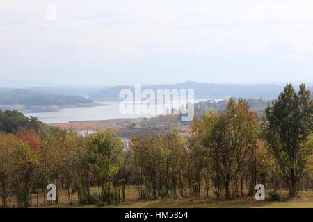 Der See mit der rauchigen Bergkette im Hintergrund an einem nebligen Morgen. Stockfoto