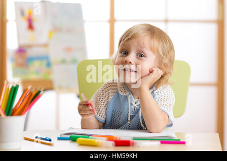 Lächelndes Kind mit einer Idee beim Zeichnen im Kinderzimmer Stockfoto