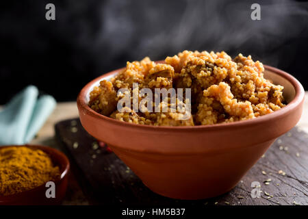 Nahaufnahme von einem Steingut-Auflauf mit Couscous mit Huhn und Gemüse auf einem rustikalen Holztisch Stockfoto