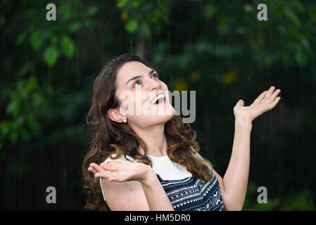 fröhliches nasse Mädchen unter tropischen Regen fällt im park Stockfoto