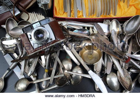 Eine Kamera und alte silberne Löffel und Messer alle warf zusammen in einem Second-Hand-shop Stockfoto