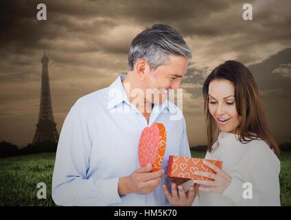 Mann Frau mit Eiffelturm im Hintergrund Geschenk anzubieten Stockfoto