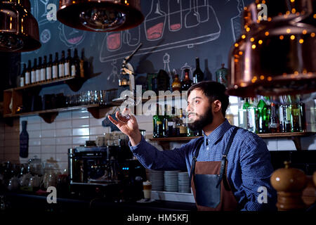 Barkeeper, Barista Arbeit schaut sauberes Glas im Restaurant hinter der Bar. Stockfoto