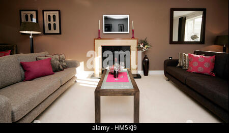 Modernes Interieur Wohnzimmer mit niedrigen Sofas in braun und Beige, Kamin, hellen Kissen, Stockfoto