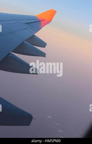 Blick durch Verkehrsflugzeug Fenster hoch über Wolken bei Sonnenuntergang Stockfoto