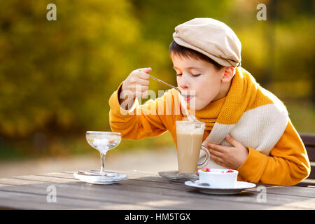 Niedlichen kleinen Jungen trinken heißen Schokolade im Café im freien Stockfoto