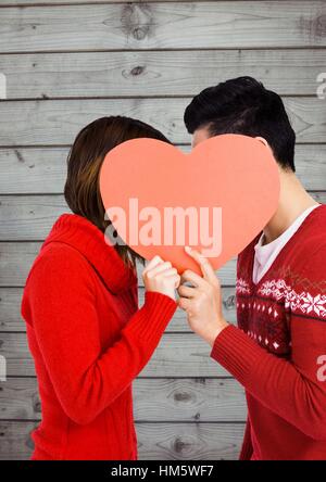 Romantisches Paar versteckt ihr Gesicht hinter Herz Stockfoto