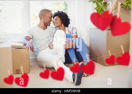 Paar im Wohnzimmer zu Hause gegen Herz hängt an einer Linie umarmen Stockfoto