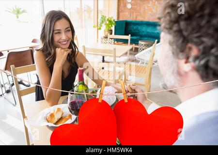 Paar beim Essen im Restaurant mit roten Herzen hängen Stockfoto