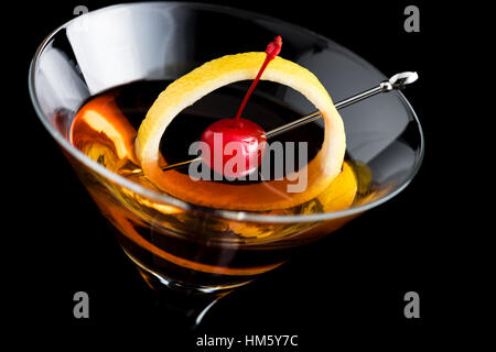 Manhattan cocktail mit Zitrone und Cocktailkirsche auf schwarzem Hintergrund Stockfoto