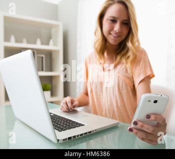 Junge Frau mit Handy und laptop Stockfoto