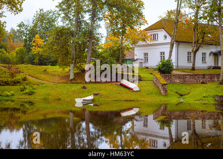 Boote auf Küste ein weißes Steinhaus in der Nähe von Teich. Palmse Manor, Estland Stockfoto