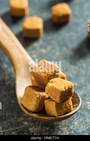 Brauner Zuckerwürfel in Holzlöffel. Stockfoto