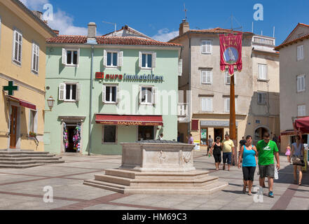 KRK, Kroatien - AUGUST 11: Menschen Spaziergang entlang der alten Brunnen und Fahne mit Wappen auf Vela Marktplatz am 11. August 2012 in Krk, Kroatien. Stadt Krk Stockfoto