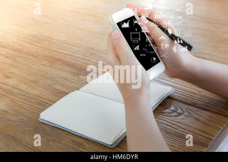 Frau mit Smartphone auf dem Tisch mit Diagramm und Chart-Symbole Stockfoto