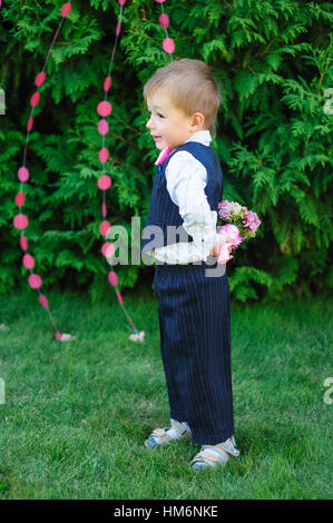 kleiner Junge hält einen Blumenstrauß im park Stockfoto