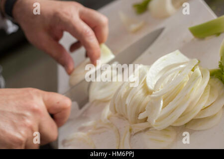 Koch schneiden Zwiebeln mit Messer auf Tafel Stockfoto