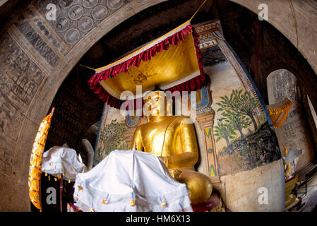 Lemyethna-Tempel Goldene Buddha-Statue Bagan Myanmar // BAGAN, Myanmar — Eine große goldene Buddha-Statue befindet sich in einem der Kardinalschreine des Lemyethna-Tempels (auch bekannt als der Tempel der vier Gesichter), einem buddhistischen Tempel, der 1223 n. Chr. während der Regierungszeit von König Htilominlo errichtet wurde. Der Tempel wurde von Anandathura, einem Minister am königlichen Hof, erbaut und verfügt über vier Schreinerräume, die nach Himmelsrichtungen gerichtet sind und jeweils eine Buddha-Statue beherbergen. Der Lemyethna-Tempel stellt eines der letzten großen Tempelprojekte der heidnischen Dynastie dar und dient als Herzstück eines ausgedehnten Klosterkomplexes aus Ove Stockfoto