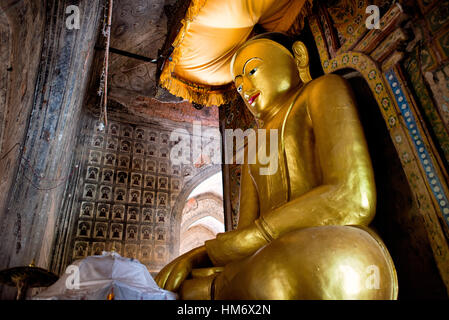 Lemyethna-Tempel Goldene Buddha-Statue Bagan Myanmar // BAGAN, Myanmar — Eine große goldene Buddha-Statue befindet sich in einem der Kardinalschreine des Lemyethna-Tempels (auch bekannt als der Tempel der vier Gesichter), einem buddhistischen Tempel, der 1223 n. Chr. während der Regierungszeit von König Htilominlo errichtet wurde. Der Tempel wurde von Anandathura, einem Minister am königlichen Hof, erbaut und verfügt über vier Schreinerräume, die nach Himmelsrichtungen gerichtet sind und jeweils eine Buddha-Statue beherbergen. Der Lemyethna-Tempel stellt eines der letzten großen Tempelprojekte der heidnischen Dynastie dar und dient als Herzstück eines ausgedehnten Klosterkomplexes aus Ove Stockfoto