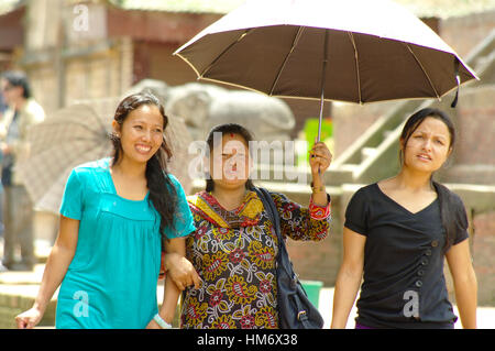 KATHMANDU, NP - ca. AUGUST 2012 - drei Frauen Spaziergang im Durbar square und Form der Sonne mit einem Regenschirm schützen. Nepal wird durch eine große Earthq gefunden werden Stockfoto