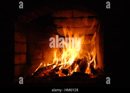 Holzscheite brennen in den gemauerten Kamin Stockfoto