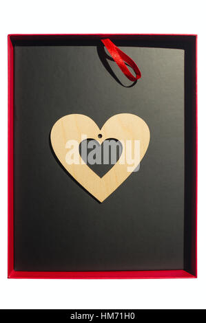 Herz aus Holz liegt auf einem schwarzen Hintergrund in der offenen roten Geschenkbox. Das Symbol der Valentinstag. Stockfoto