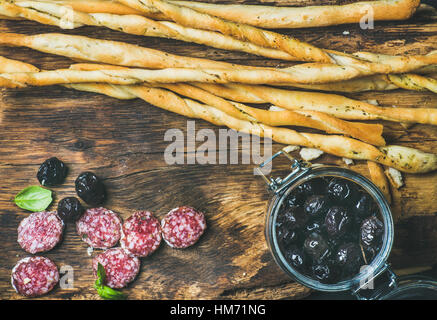 Grissini Brot-Sticks, Wurst, schwarzen Oliven auf hölzernen Hintergrund Stockfoto