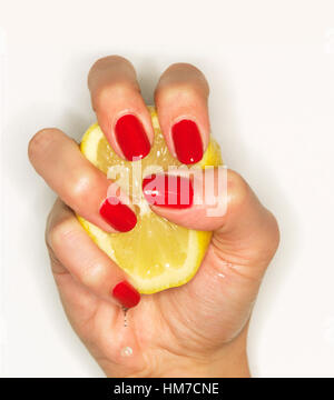 Hand der Frau mit rotem Nagellack Zitrone auspressen Stockfoto