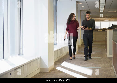 Junge Menschen gehen nebeneinander im Korridor mit digital-Tablette Stockfoto