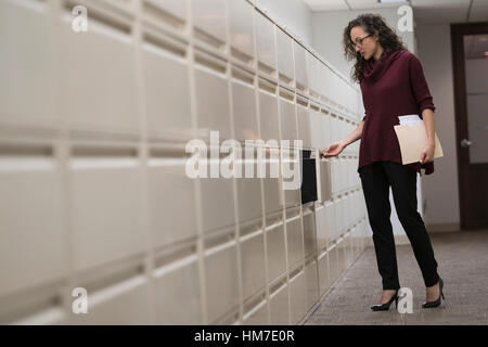 Junge Frau Eröffnung Schublade im Korridor Stockfoto