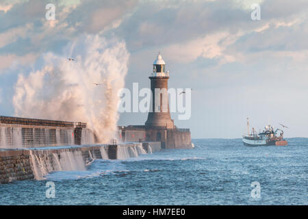 Angelboot/Fischerboot verlassen den Fluss Tyne vorbei am Leuchtturm und North Pier als mächtige Wellen über während einer Sturmflut Stockfoto