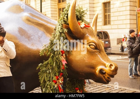 Touristen, die das Fotografieren mit der Aufladung Stier Skulptur in einen Weihnachtskranz von Arturo Di Modica, Bowling Green Park, New York Stockfoto