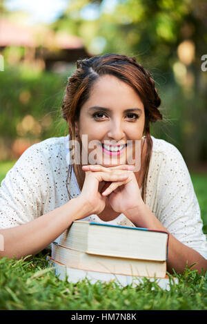 Stütze dich auf lächelndes Mädchen Bücher im Park Rasen Stockfoto