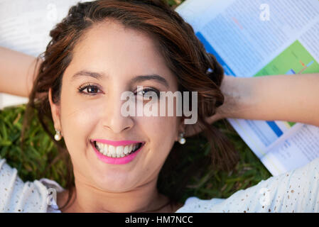 Mädchen auf dem Rücken auf Bücher verlegen und lächelnd Stockfoto