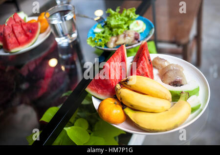 Platte mit Wassermelonen, Bananen, Orangen und Salat im Restaurant in Thailand Stockfoto