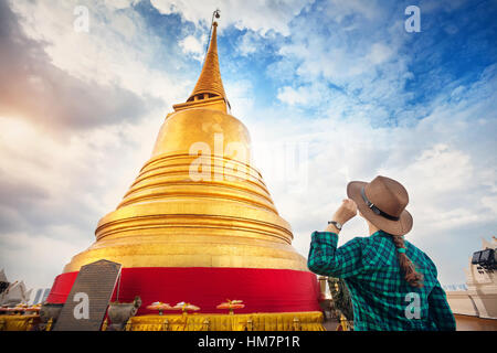 Tourist-Frau in Hut und grün kariertes Hemd Blick auf große goldene Stupa in Wat Saket Tempel in Bangkok, Thailand Stockfoto